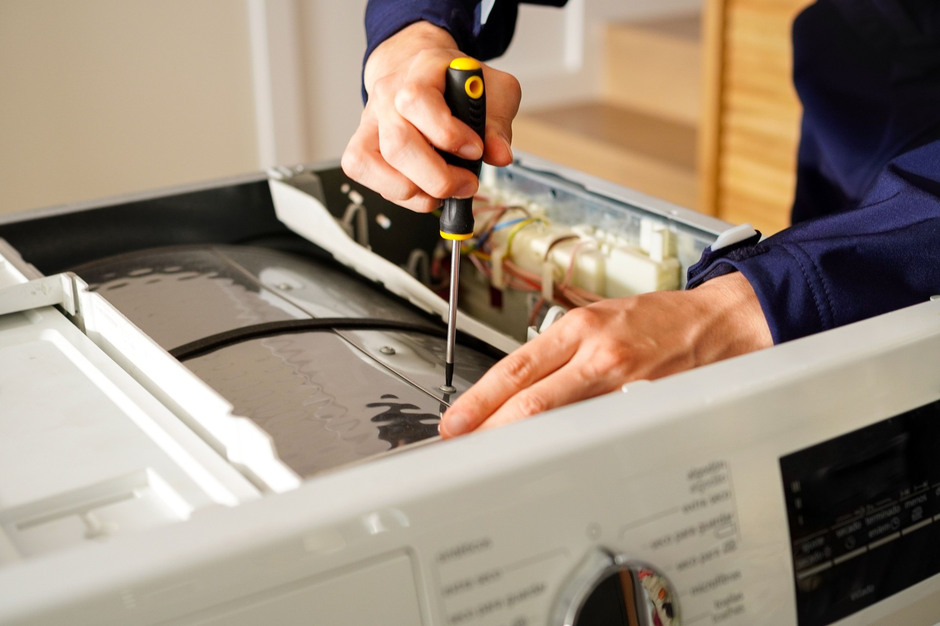 Un ingeniero de electrodomésticos reparando una lavadora rota